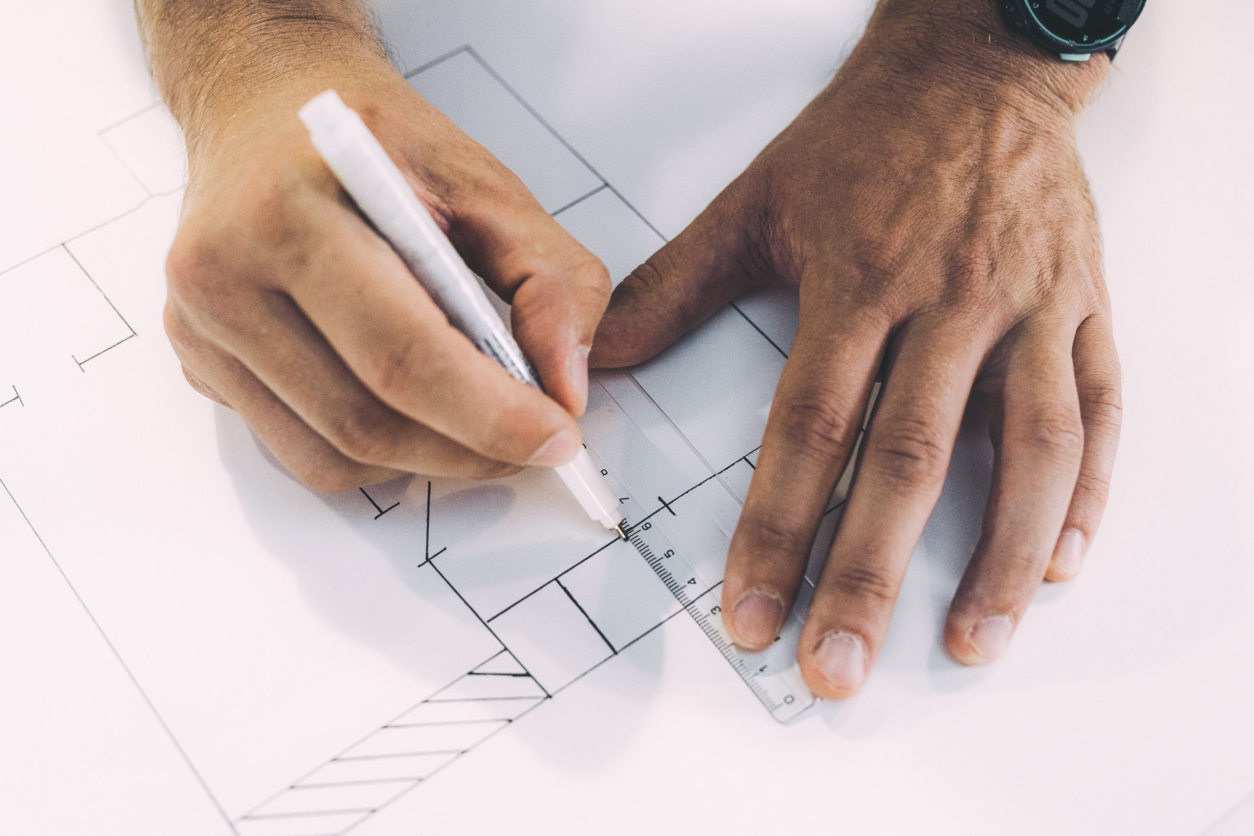 In the photo, you can see someone using a ruler and a pen to make a technical drawing or building plan.