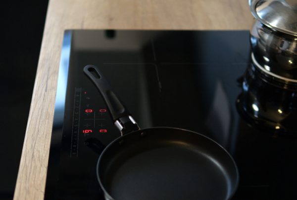 Modern black induction hob with pots and pans on active cooking zones – sleek, functional and stylish.