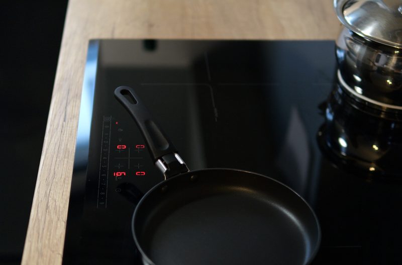 Modern black induction hob with pots and pans on active cooking zones – sleek, functional and stylish.