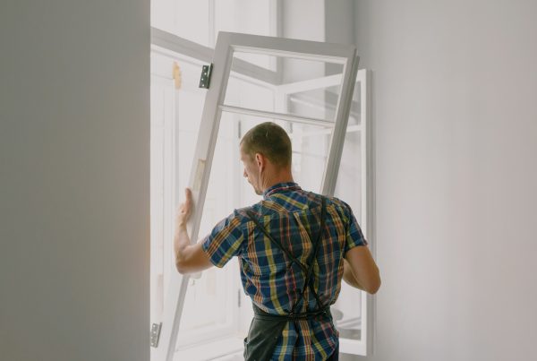 Monteur plaatst een nieuw kozijn in de gevel van een woning tijdens een renovatie