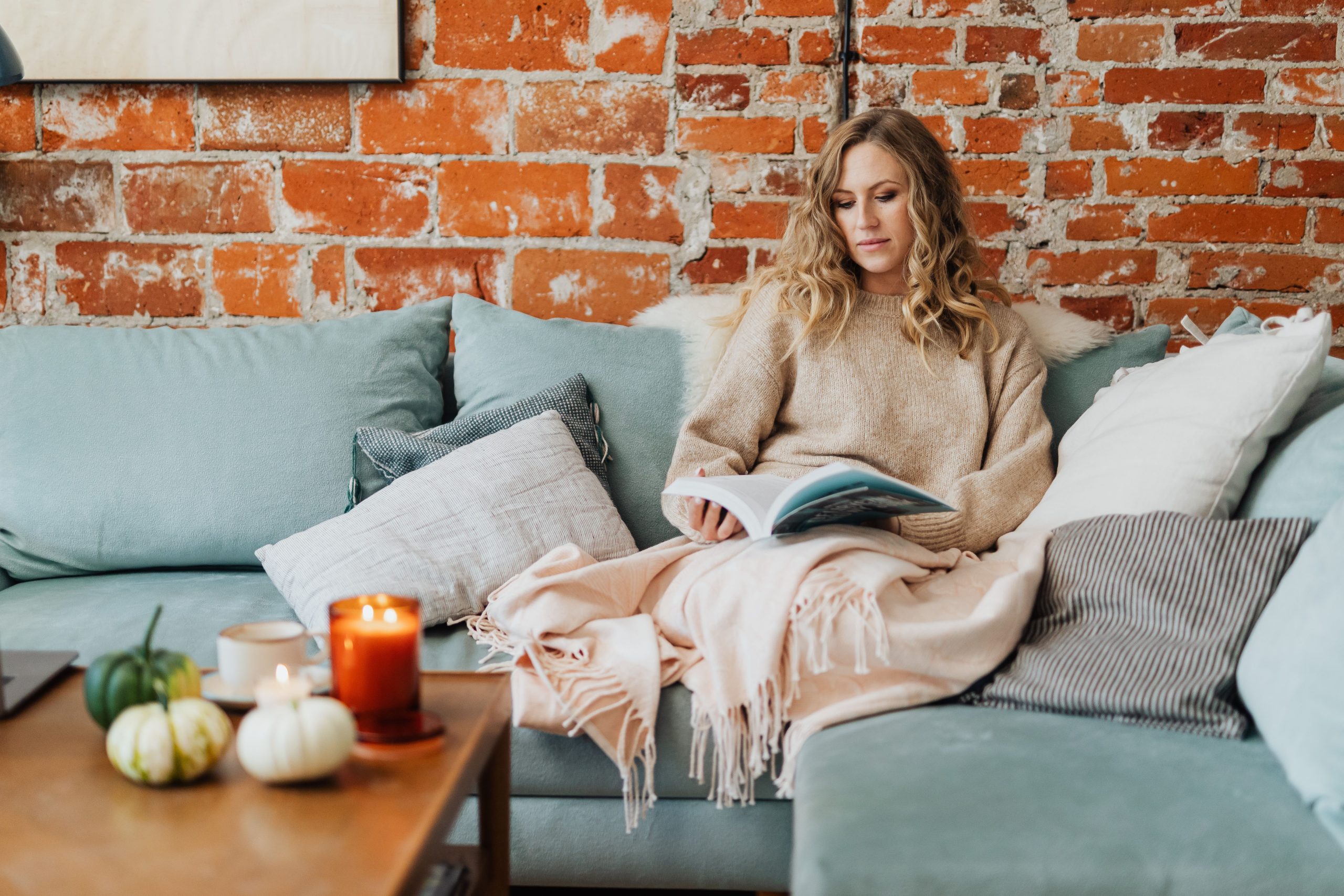 Woman with a blanket on the sofa during the first cold evening of autumn