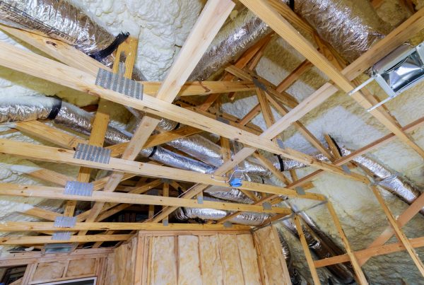 Vakman brengt isolatiemateriaal aan tussen de gordingen van een schuin dak tijdens een renovatie