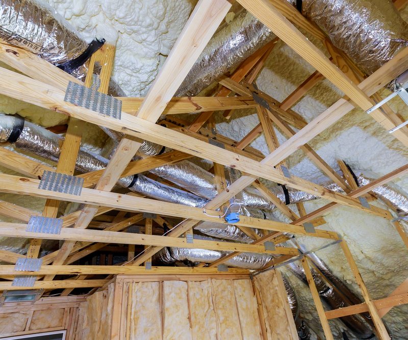Vakman brengt isolatiemateriaal aan tussen de gordingen van een schuin dak tijdens een renovatie