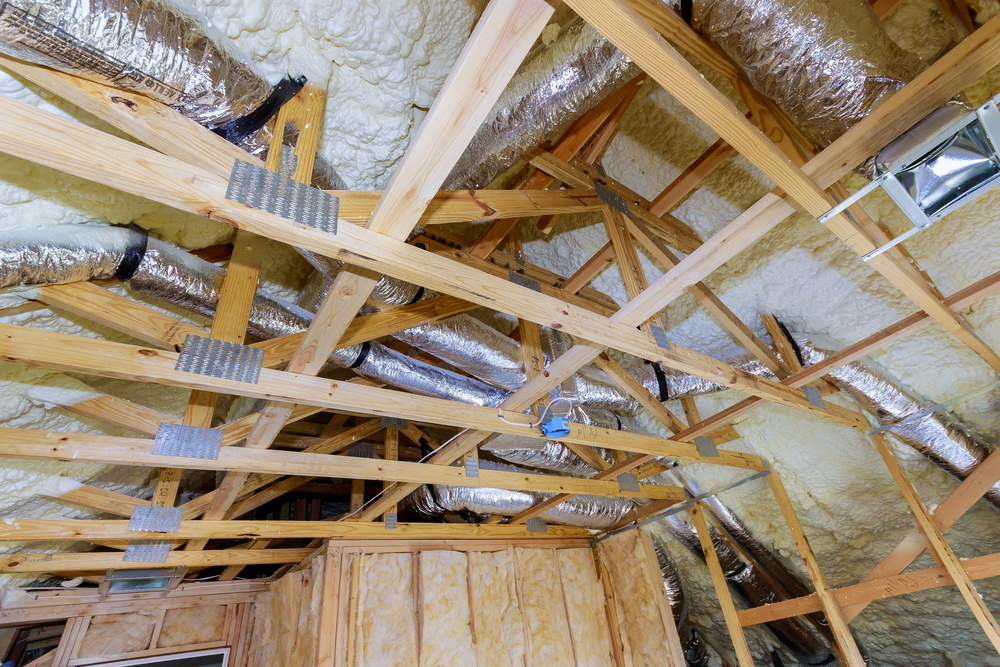 Vakman brengt isolatiemateriaal aan tussen de gordingen van een schuin dak tijdens een renovatie