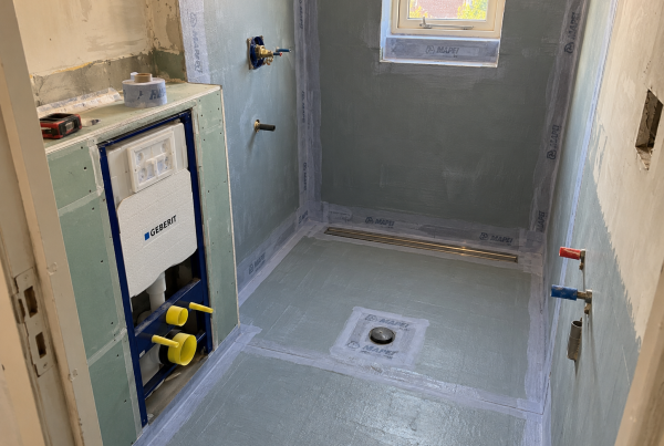 Bathroom under construction with new pipework and waterproofing applied before tiling